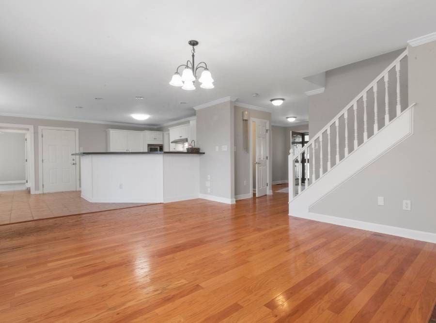 Open-concept living room and kitchen with polished hardwood flooring and neutral gray walls