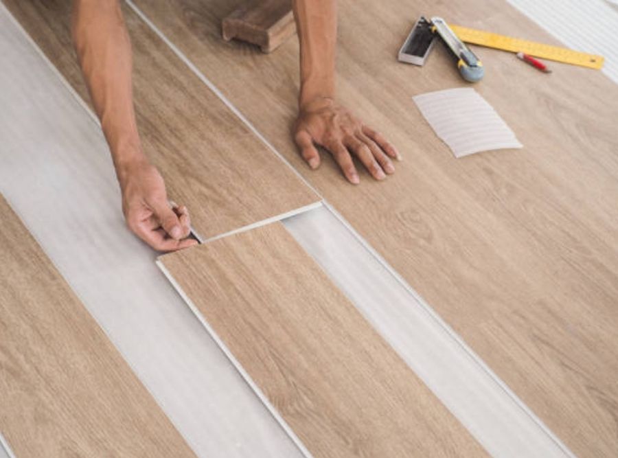 Worker installing luxury vinyl plank (LVP) flooring with wood-look finish